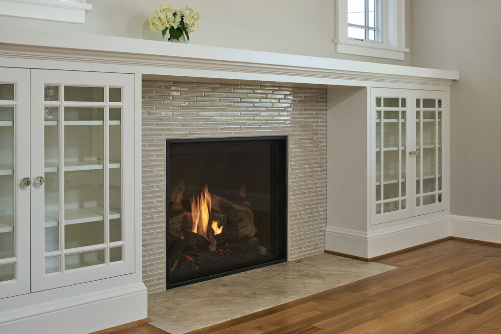 The fireplace is a sealed gas unit, surrounded by traditional, custom built-in cabinetry. The tile is by Encore Tile and the hearth is limestone.
