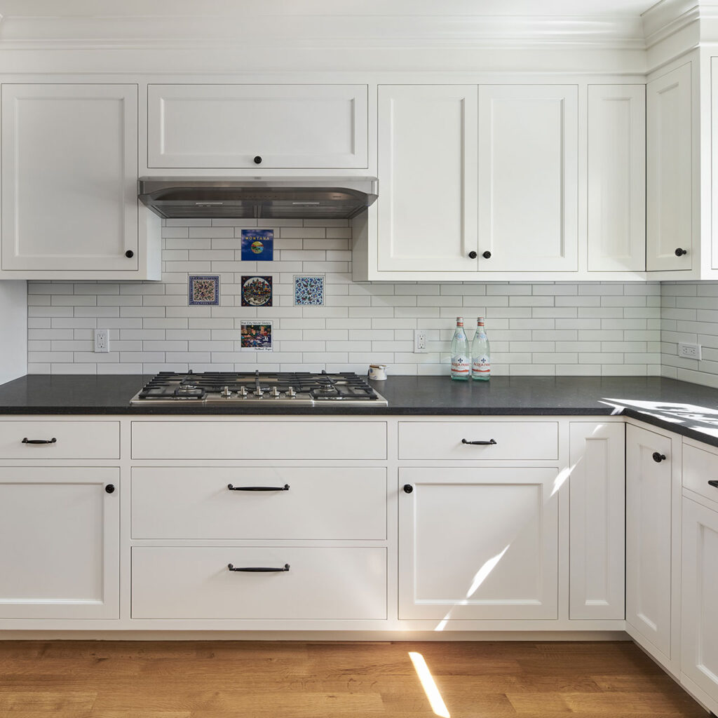 The tile backsplash over the range features trivets that the owner collected over the course of her travels.