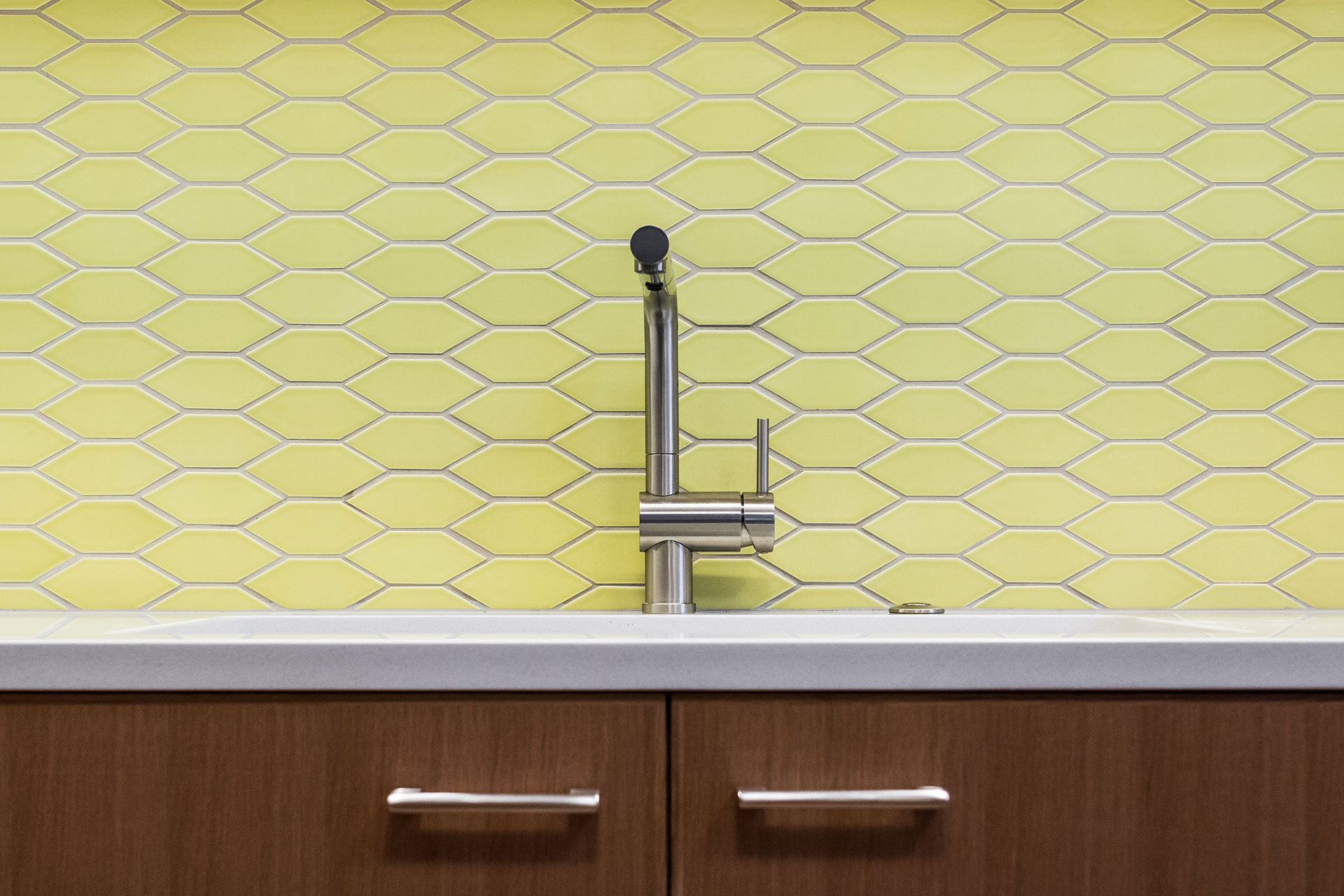 The kitchen tile backsplash features yellow, oblong hexagon tiles at the Alameda Modern.