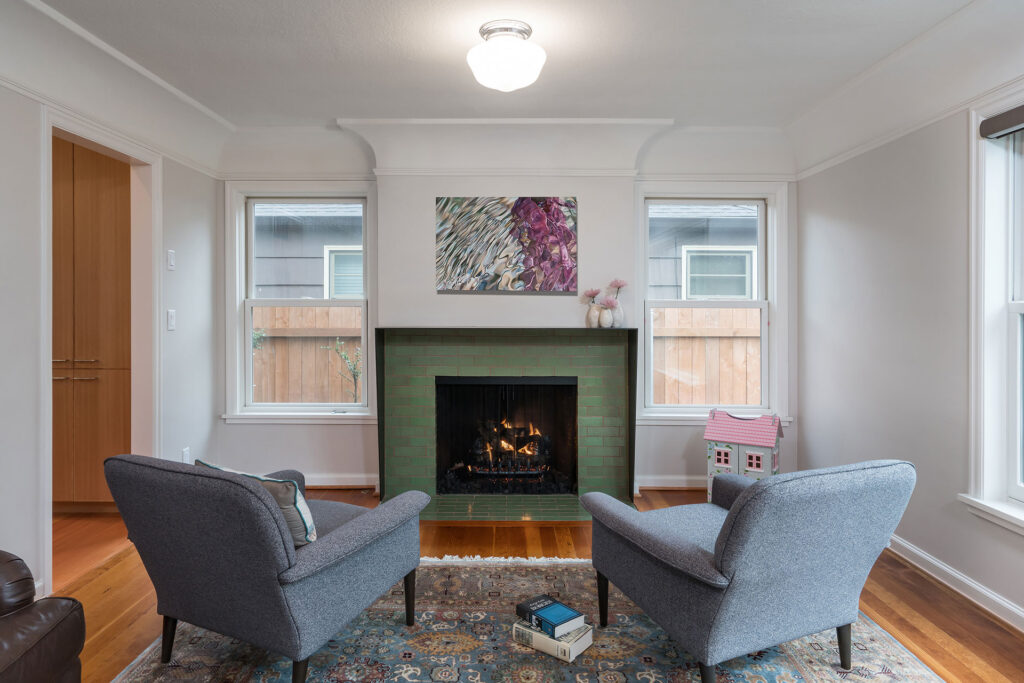 The remodeled fireplace features green brick tile and a custom blackened steel mantle.