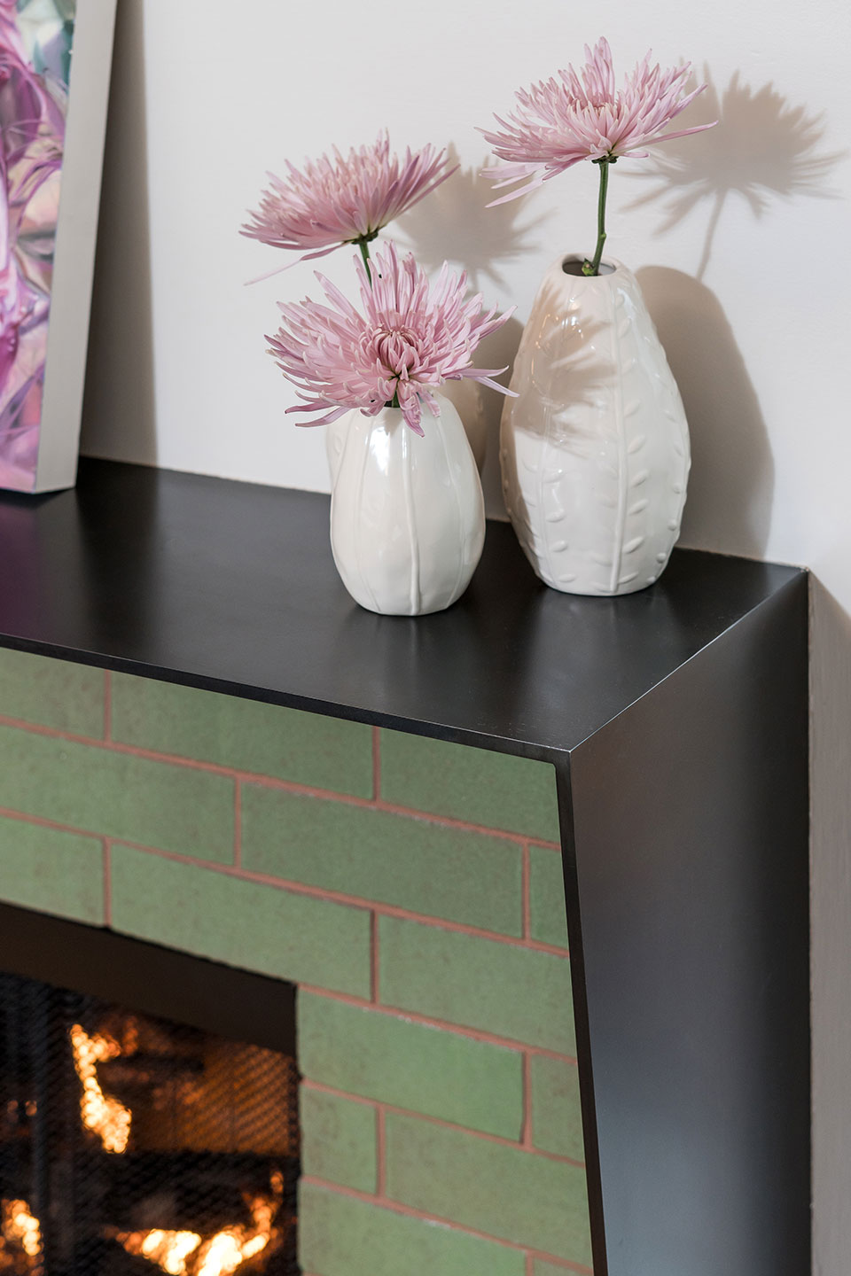 The fireplace features green brick tile and a custom blackened steel surround at the Concordia Renovation.