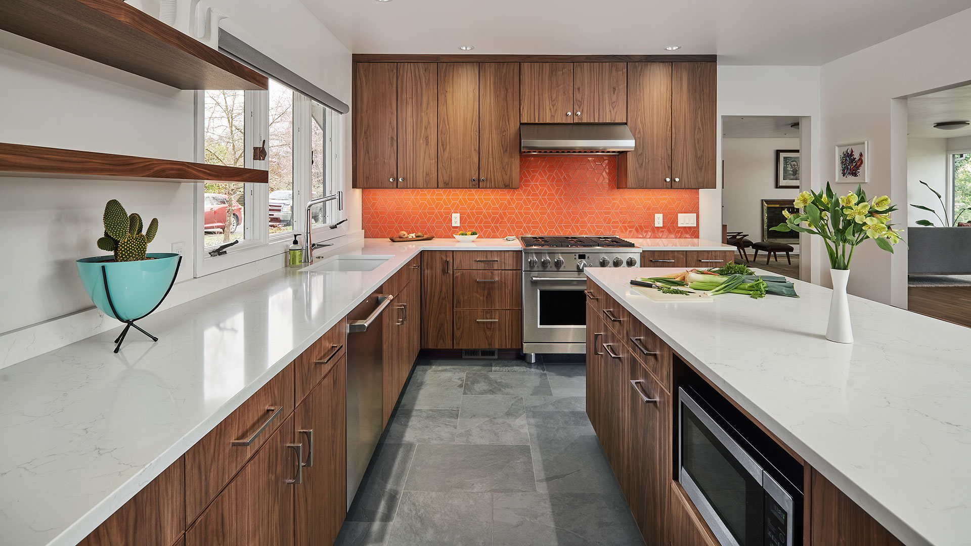 The renovated kitchen at the Eastmoreland Remodel features a large island and bright tomato orange backsplash tile.