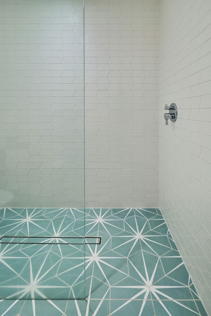 Walk in shower has large format hexagon floor tile and split hexagon wall tile.