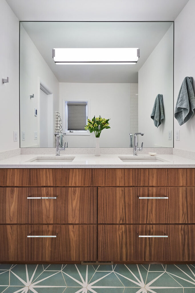 The bathroom at the Eastmoreland Remodel features a walnut vanity with full size mirror and porcelain tile.