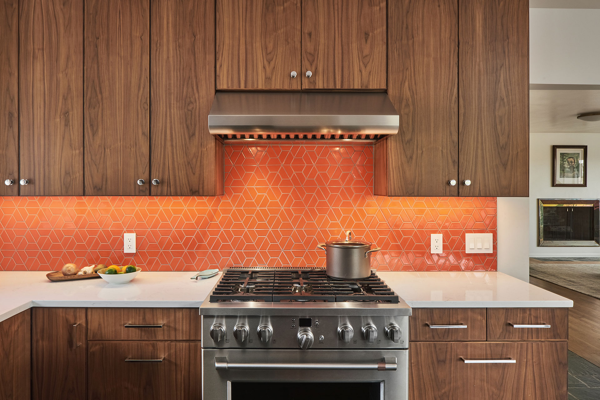 Kitchen with walnut cabinetry and orange tile backsplash.