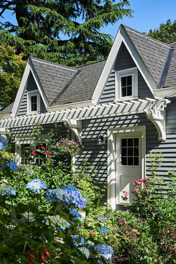 The new garage is surrounded by a lush flower garden filled with roses and hydrangea.