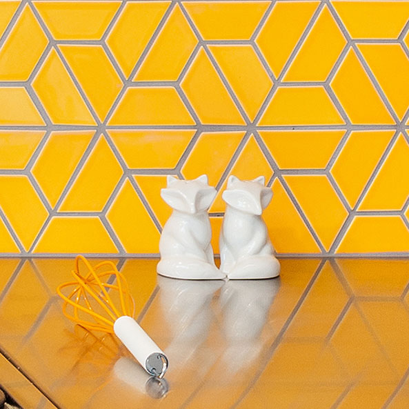 Bright yellow-orange colorful tile with a split hexagon shape is used for a kitchen backsplash.