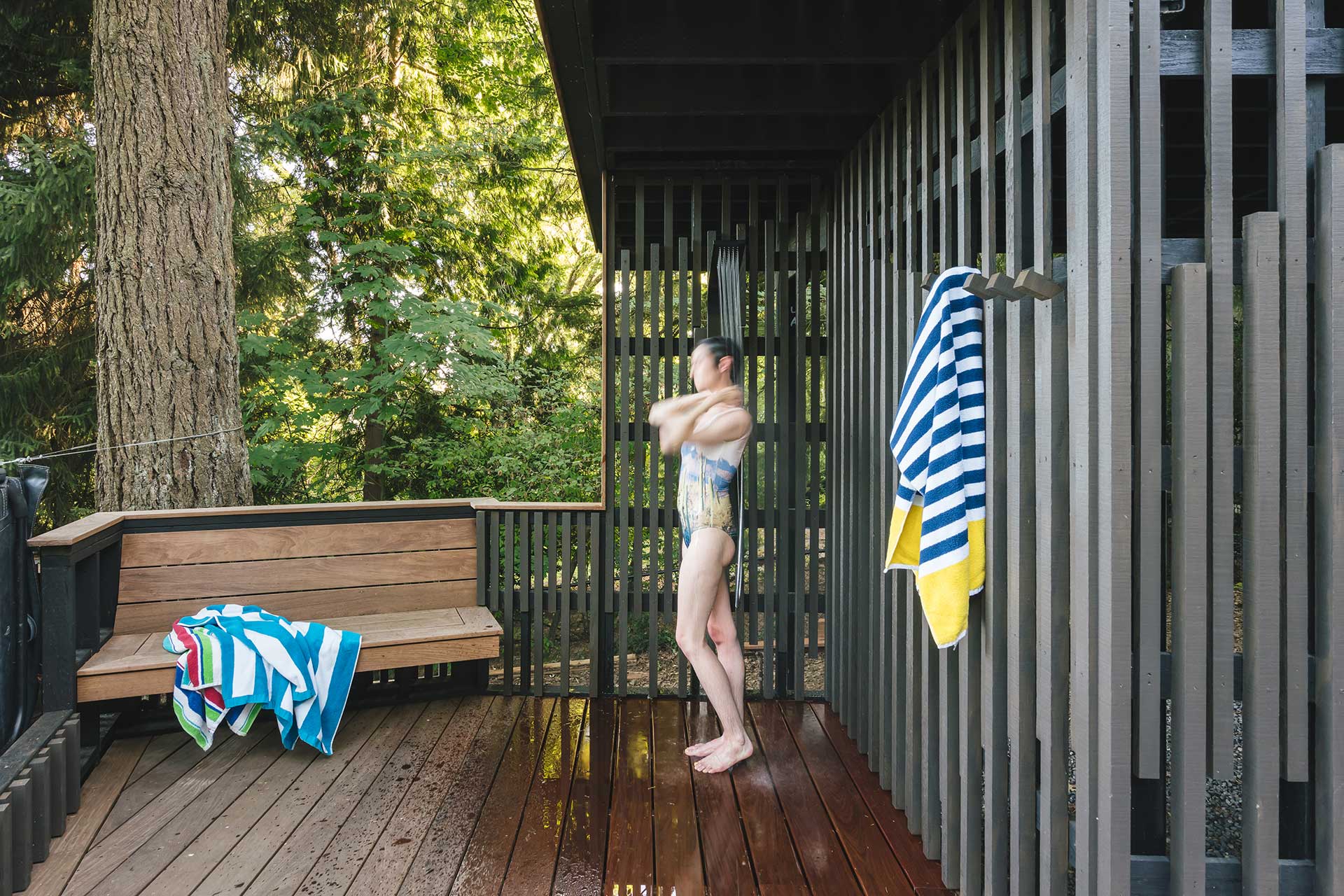 The lower level of the multilevel deck features an outdoor shower and a custom ipe-wood bench.