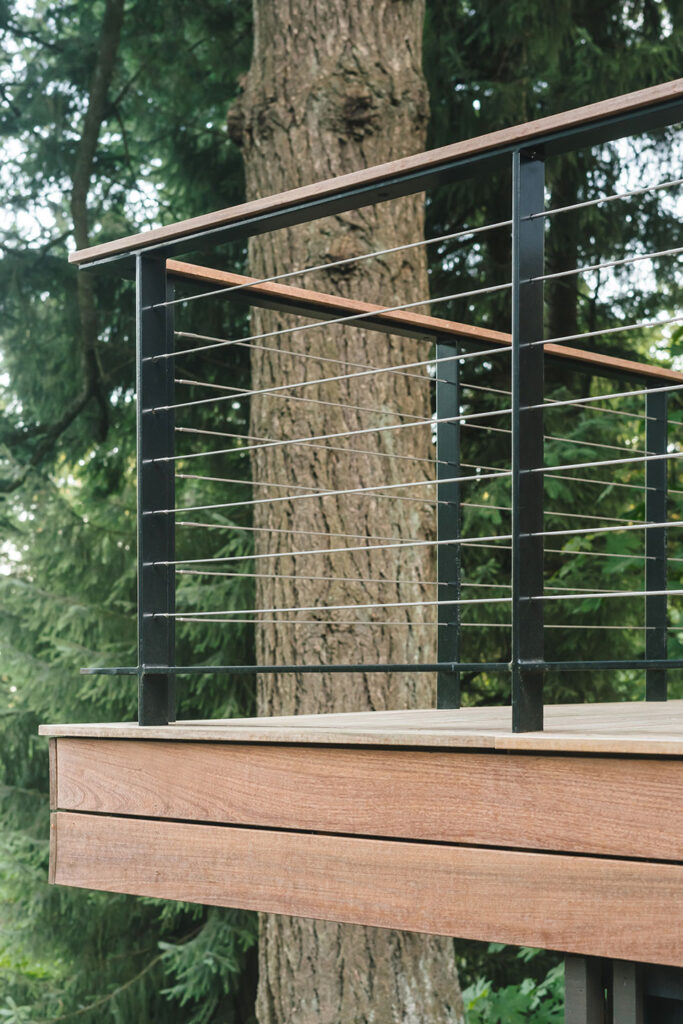 The multilevel deck is crafted from ipe wood. The guardrail is a custom guardrail fabricated from black powder-coated steel and infilled with cable rail.