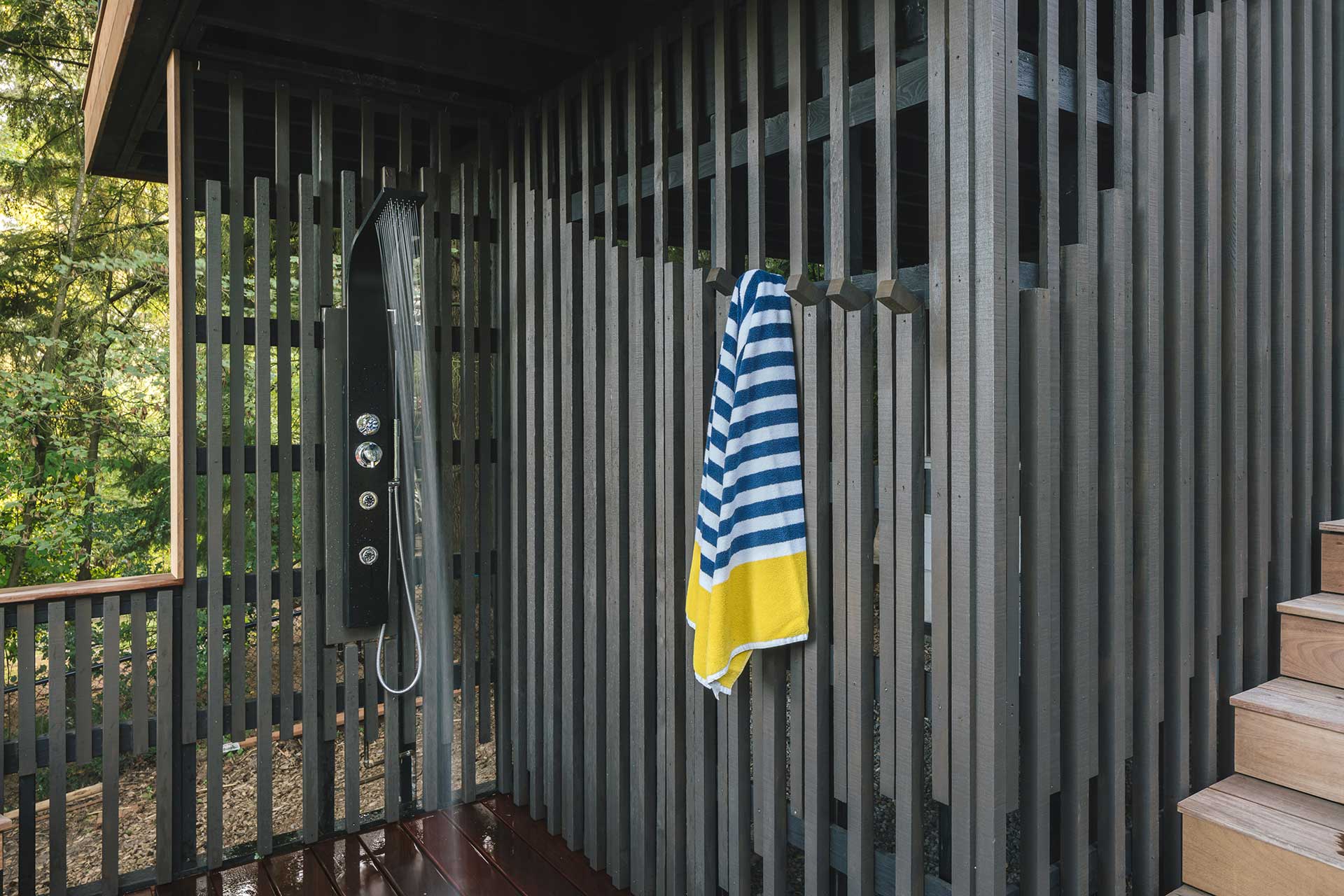 Outdoor shower with towel hooks crafted from the same material as the enclosure.