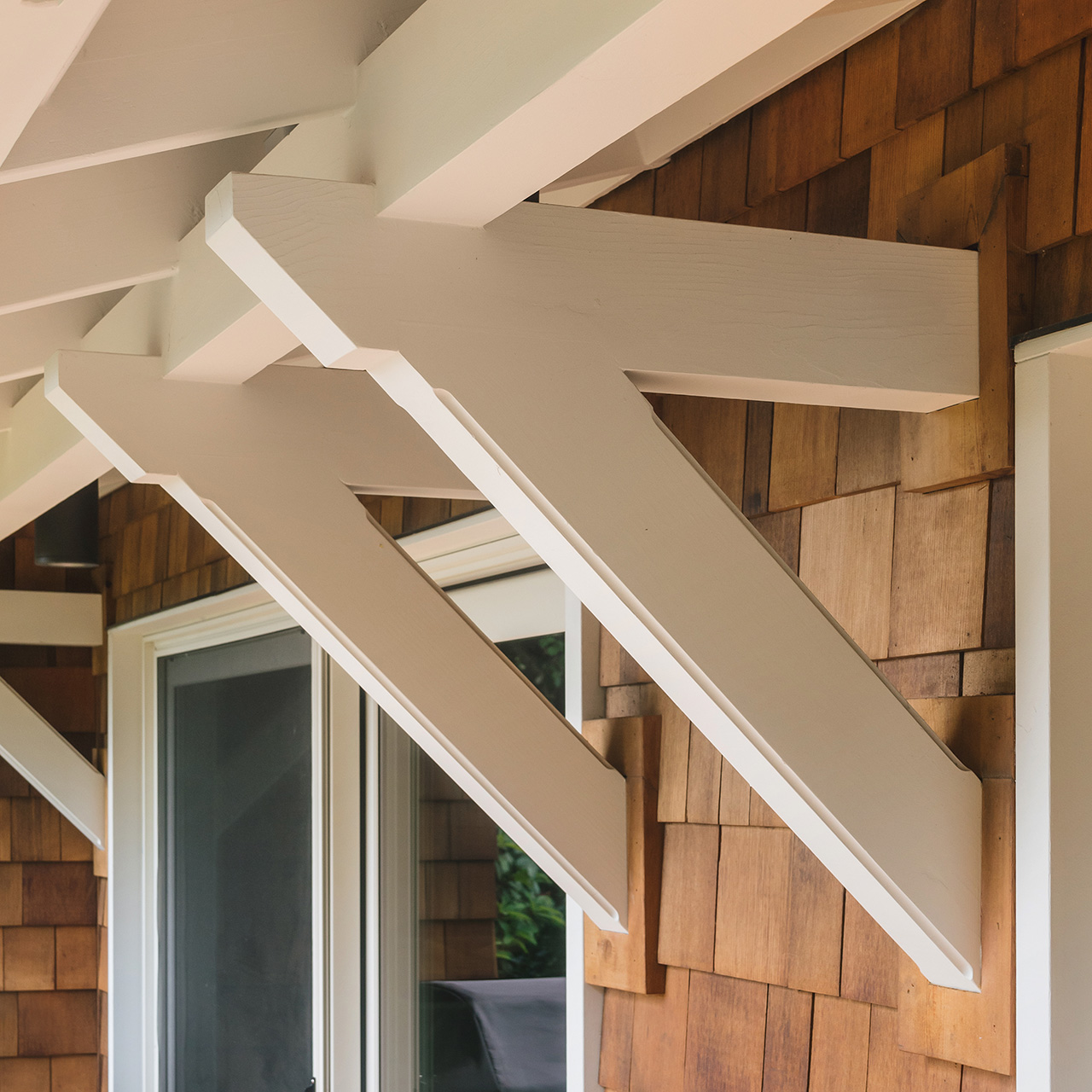 Custom wood brackets support a canopy over the sliding glass doors at the rear of the Hillside House.