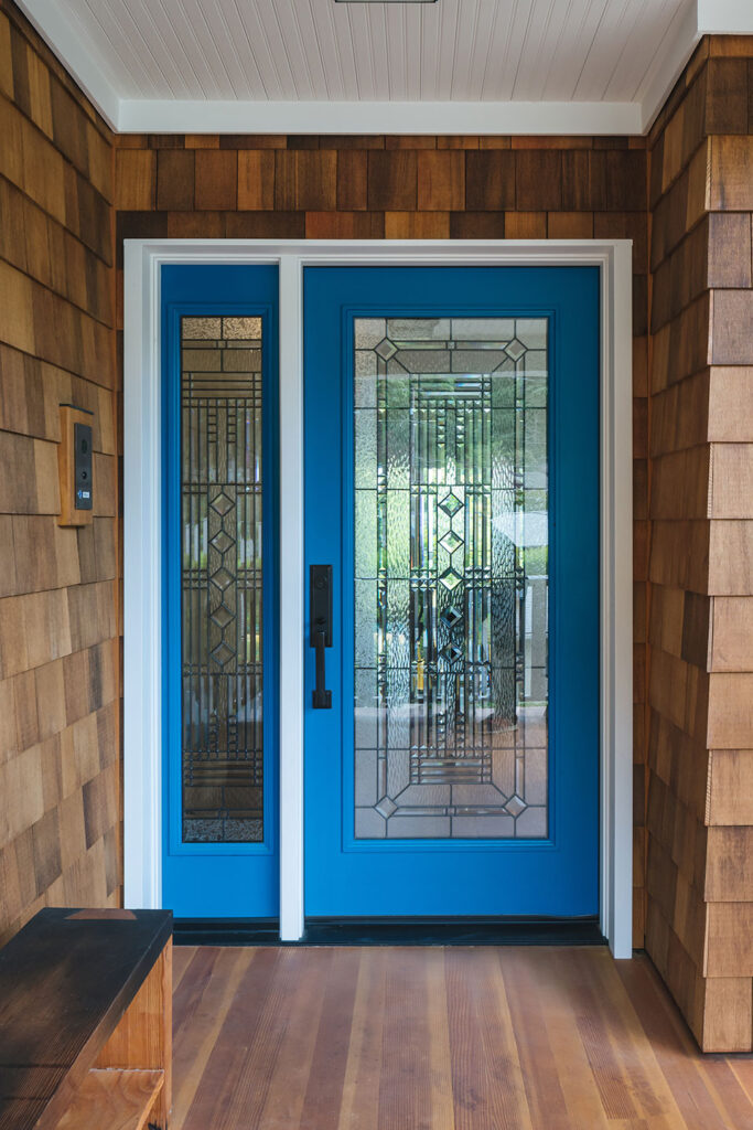 A custom glass front door and sidelite painted bright blue welcome visitors to the Hillside House.