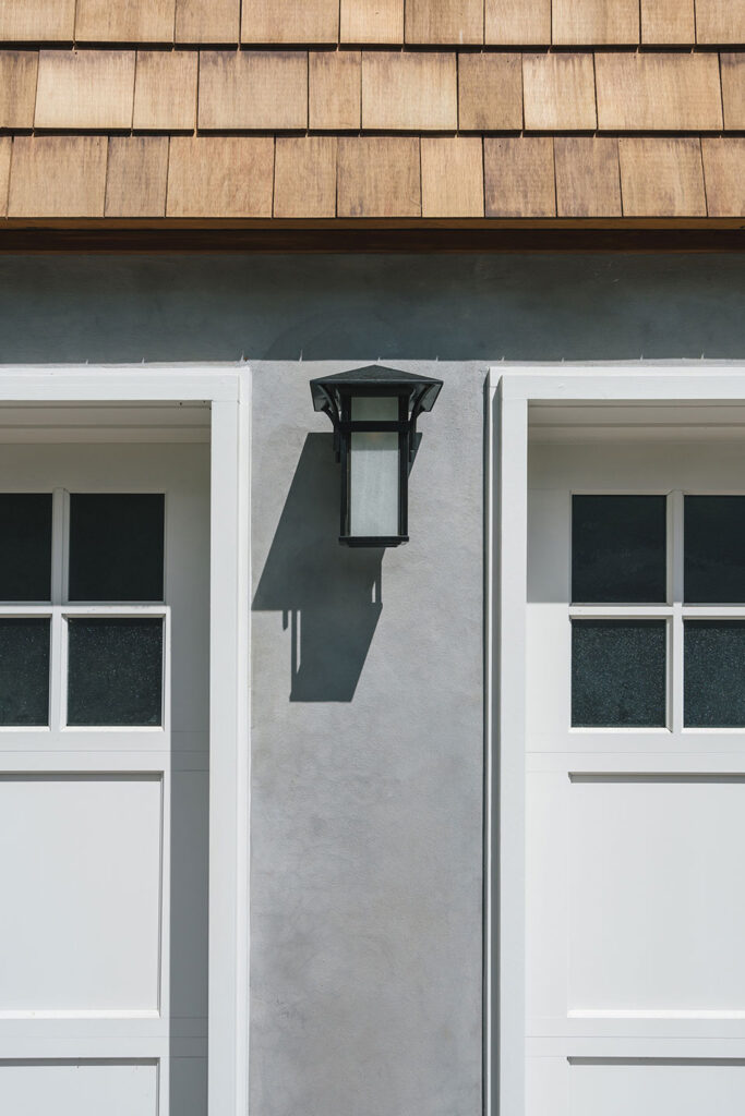 Craftsman style wall sconces at the sides of garage doors.
