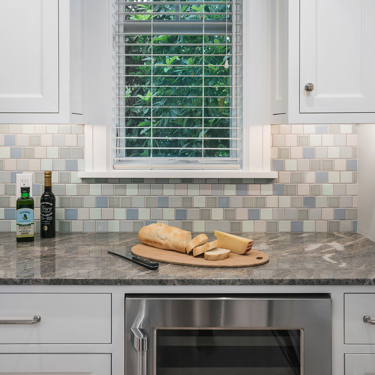 Granite countertops with a custom tile backsplash create an inviting space to prepare meals in the Hillside House kitchen.
