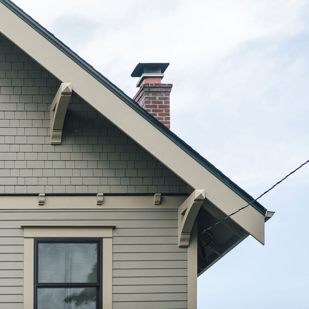 The exterior of the renovated Alameda Craftsman features traditional details including: lap siding, window trim with parting bead and crown, eave brackets, shingles, corbels, and an oversized barge board.