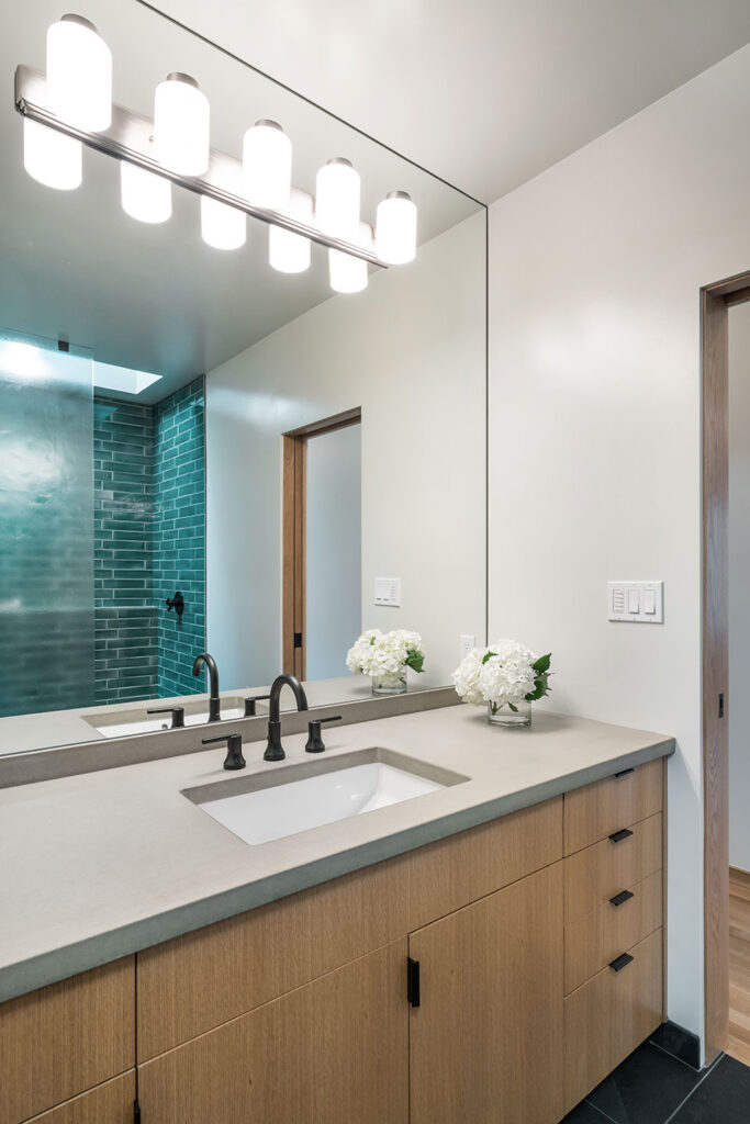 The vanity at whole house renovation is crafted from white oak and the countertop is concrete.