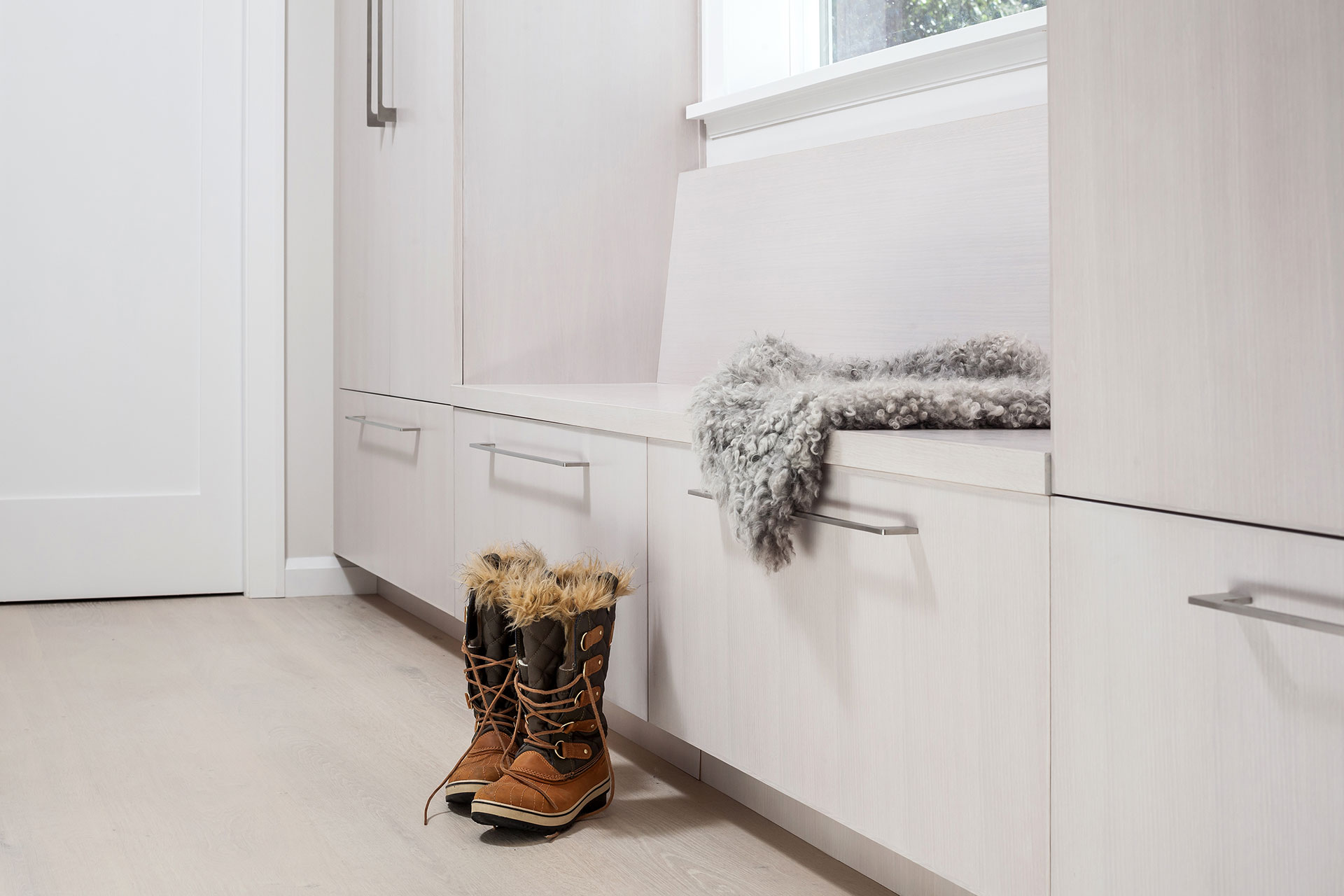 Warm winter boots sit next to the custom bench and cabinetry in the primary suite at the Modern Farmhouse.