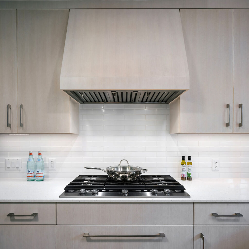 The stove hood is crafted from the same white oak as the adjacent cabinetry at the Modern Farmhouse.