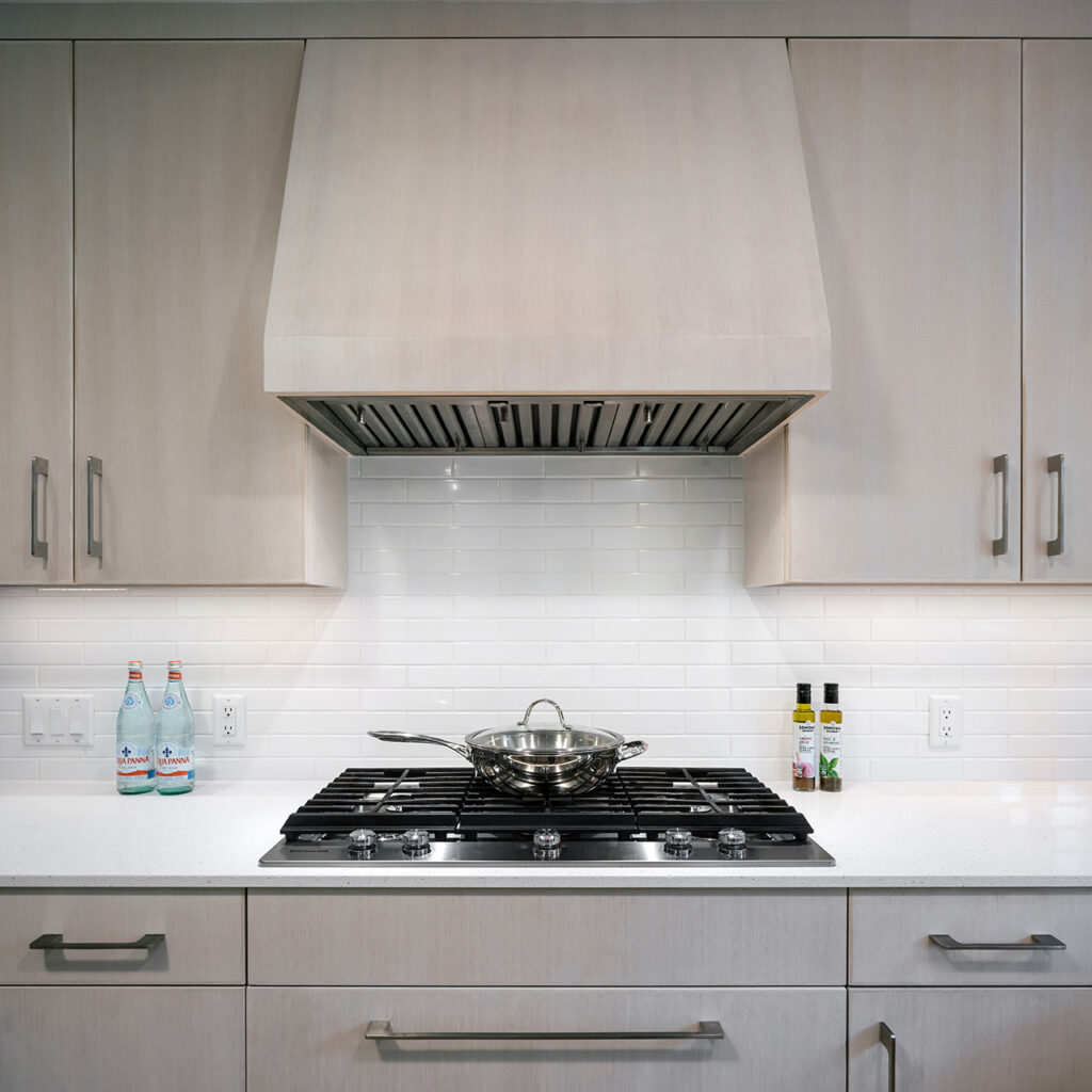 The kitchen features white oak cabinetry and a handcrafted white subway tile backsplash in this modern farmhouse remodel.