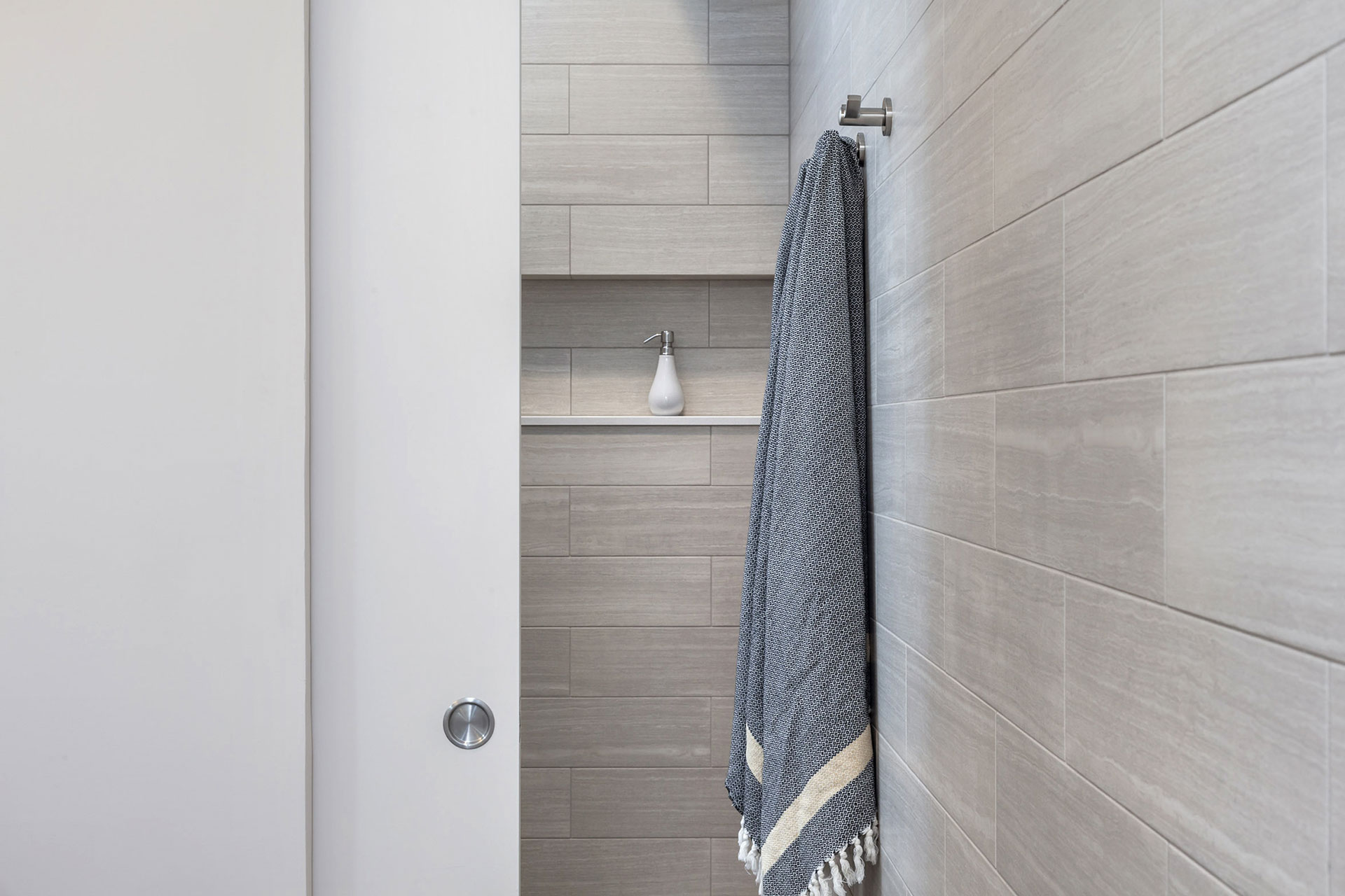 A towel hangs on a hook just outside of the shower in the primary bathroom.