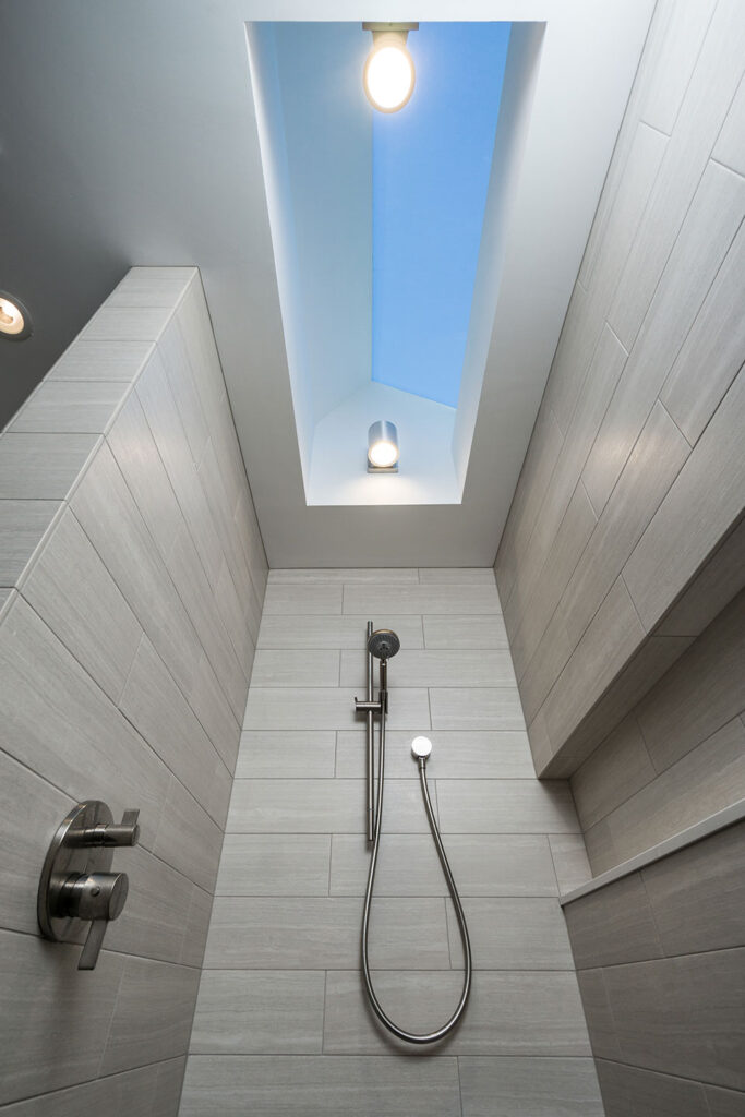A large skylight bathes the shower with natural light in the primary bathroom at the Modern Farmhouse.