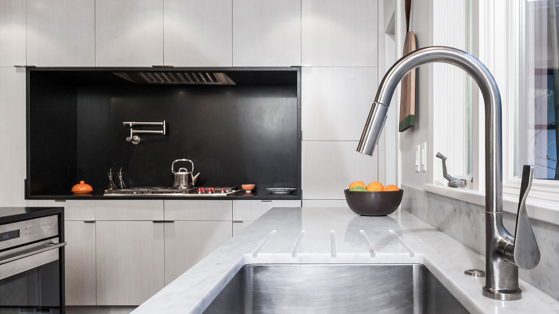 A stainless steel sink faces the front window in this mid-century modern renovation.