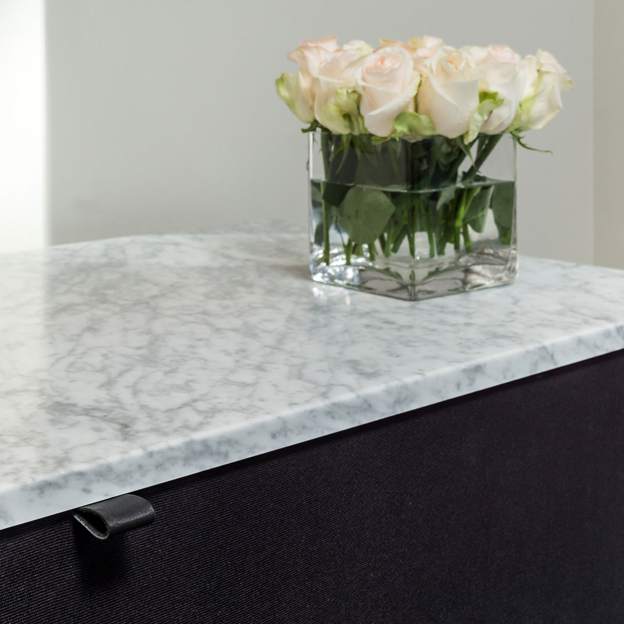 Cabinetry features Carrera marble and custom leather cabinet pulls.