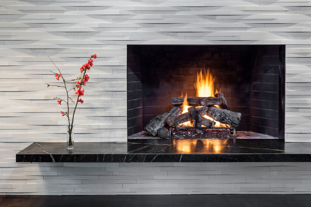 A black marble slab cantilevers from the wall to create a floating hearth for the fireplace in this mid-century modern remodel.