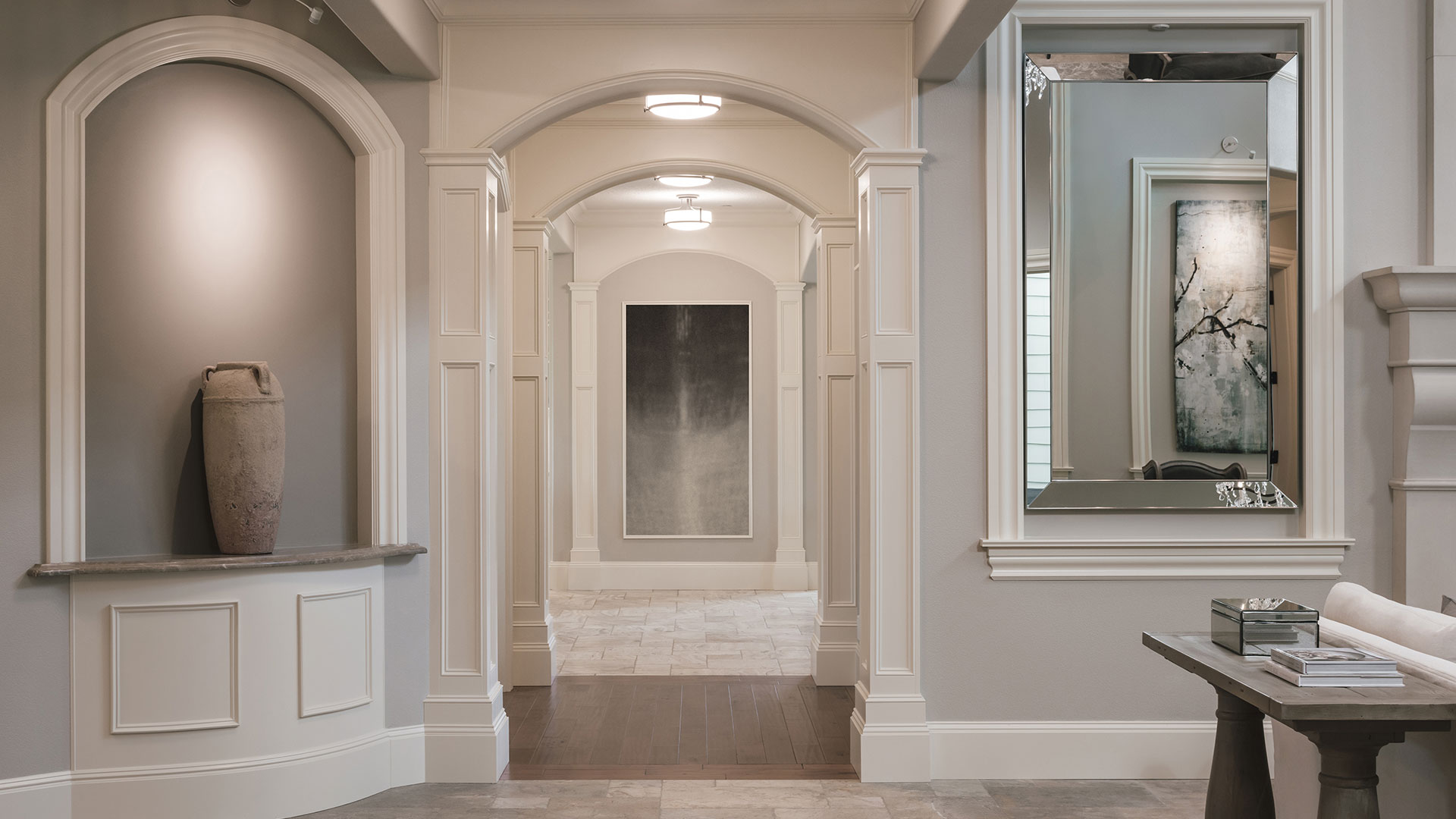 This is a view from the entry hall looking towards the kitchen after the whole house interior remodel. Repeated arches frame the artwork at the end of the hall.