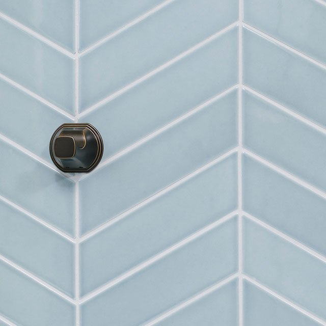 A towel hook is mounted inside the shower on blue ceramic tile.