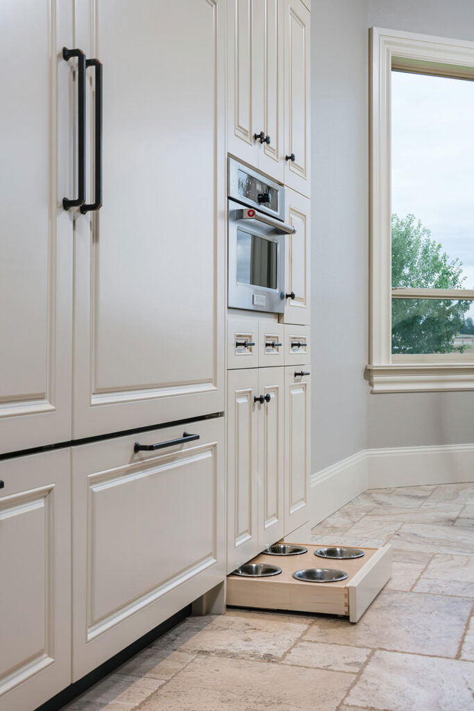 A pull-out drawer in the toe kick of the kitchen cabinetry holds dog bowls for feeding time.