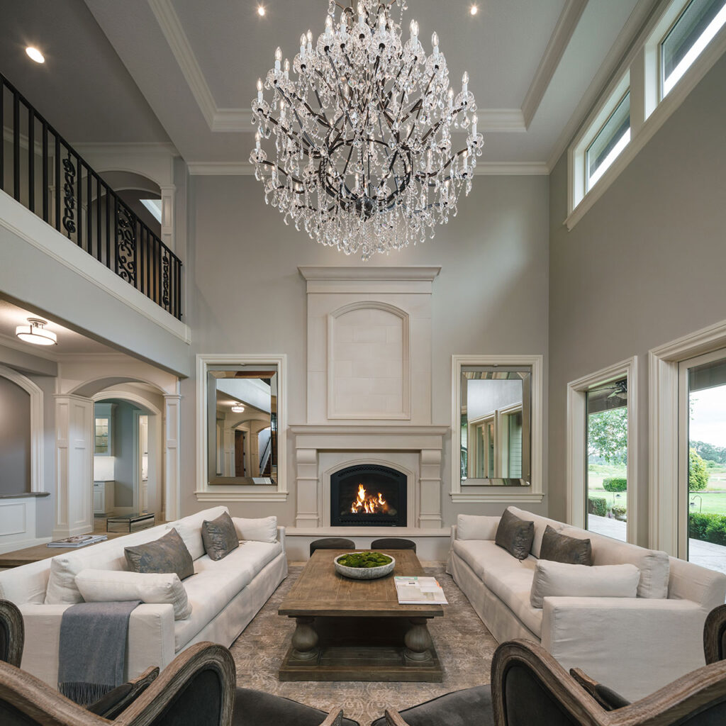 The living room at features a glass chandelier and a large fireplace after the whole house interior remodel.