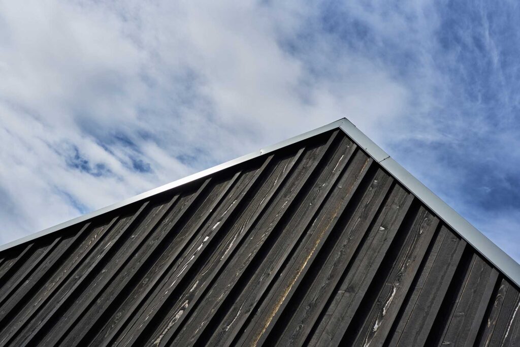 The studio has a standing seam metal roof and black-stained board and batten siding.