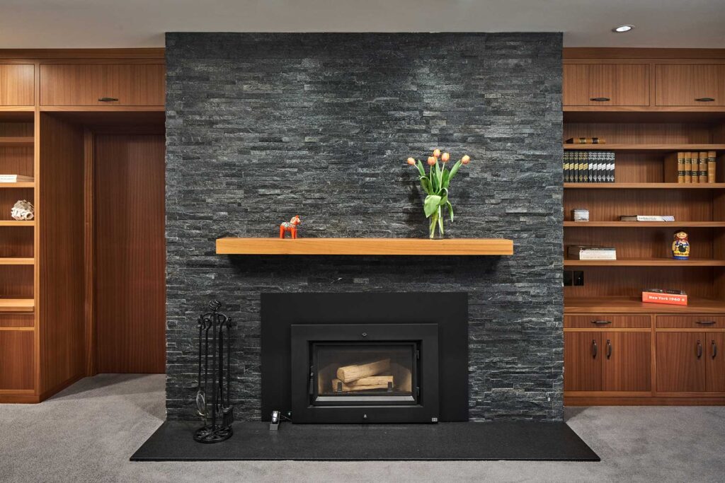 Cut black stone covers the original brick fireplace in this basement renovation.