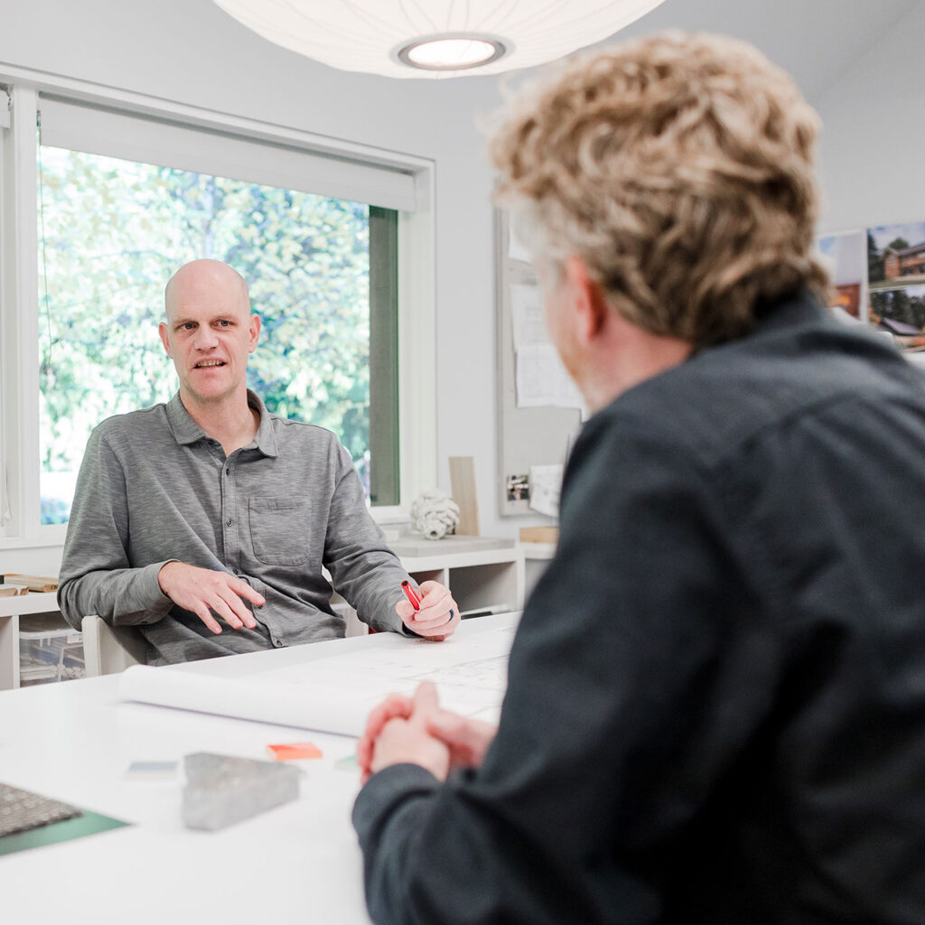 Adam Christie discussing drawings with a client at his Portland architecture office.