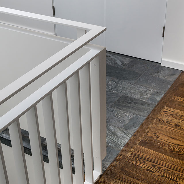 The white stair guardrail, gray slate floor, and stained hardwood floors come together in the renovated entry hall.