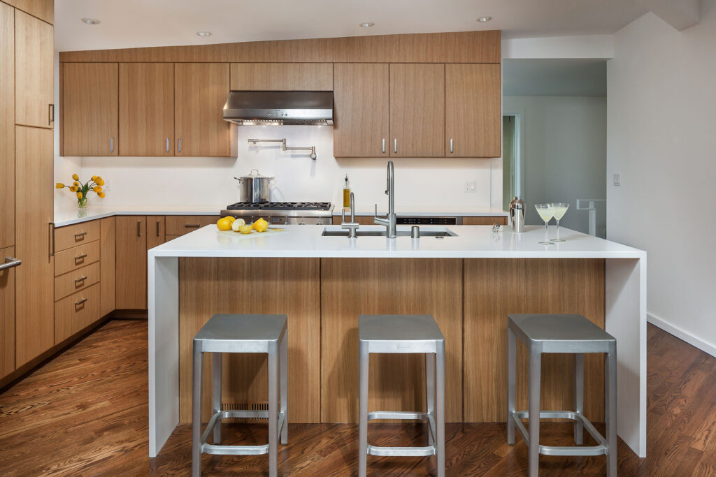 The renovated kitchen features a large island with a kitchen sink and space for seating.