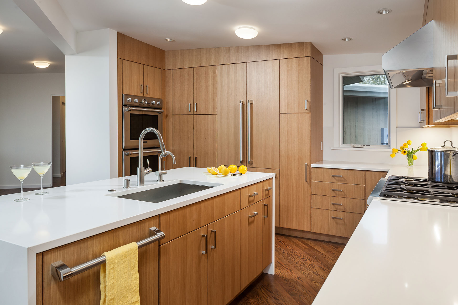 The renovated kitchen features a built in refrigerator and dishwasher with custom panels that match the adjacent cabinetry.