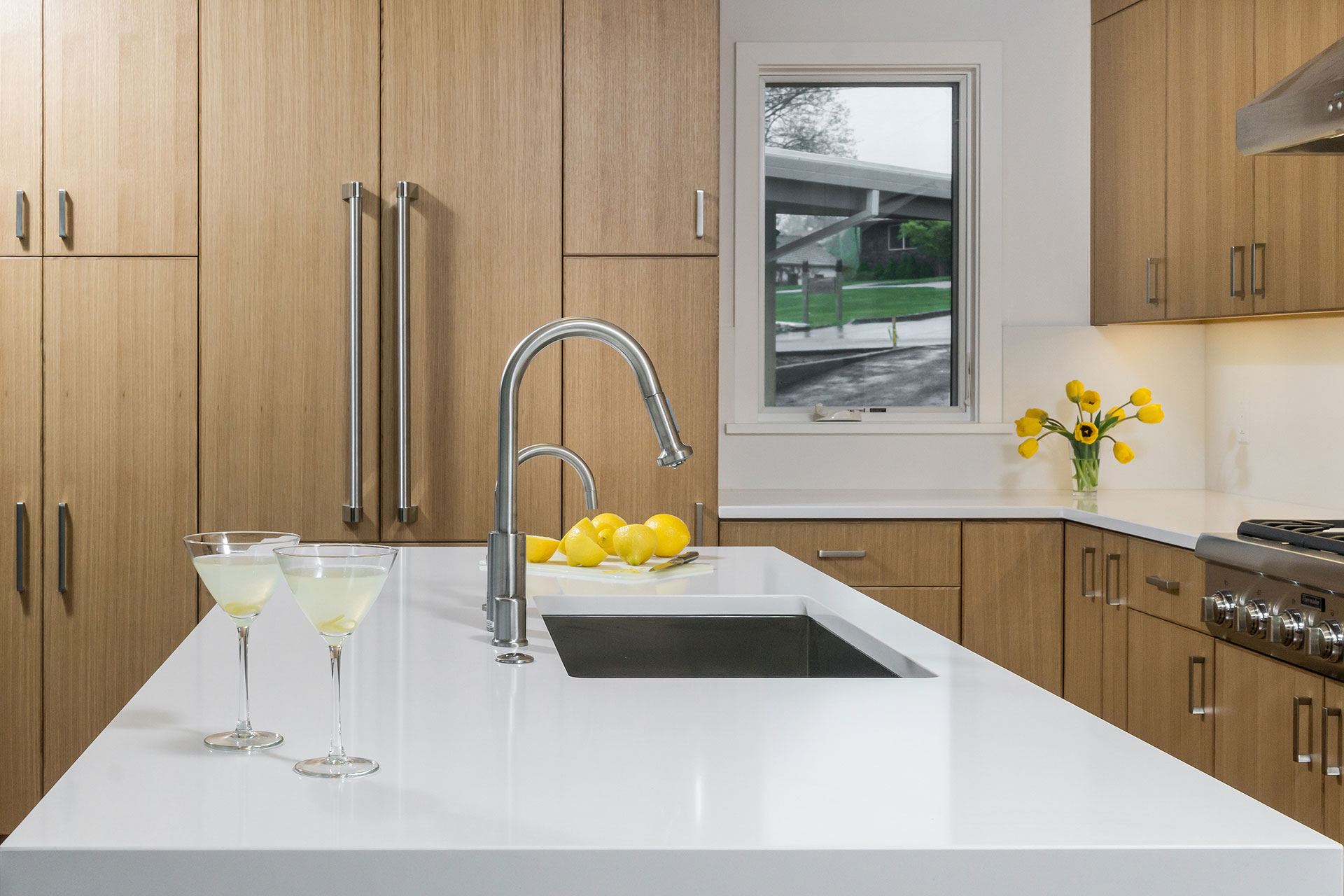 The kitchen island is made of white quartz and features a waterfall edge.