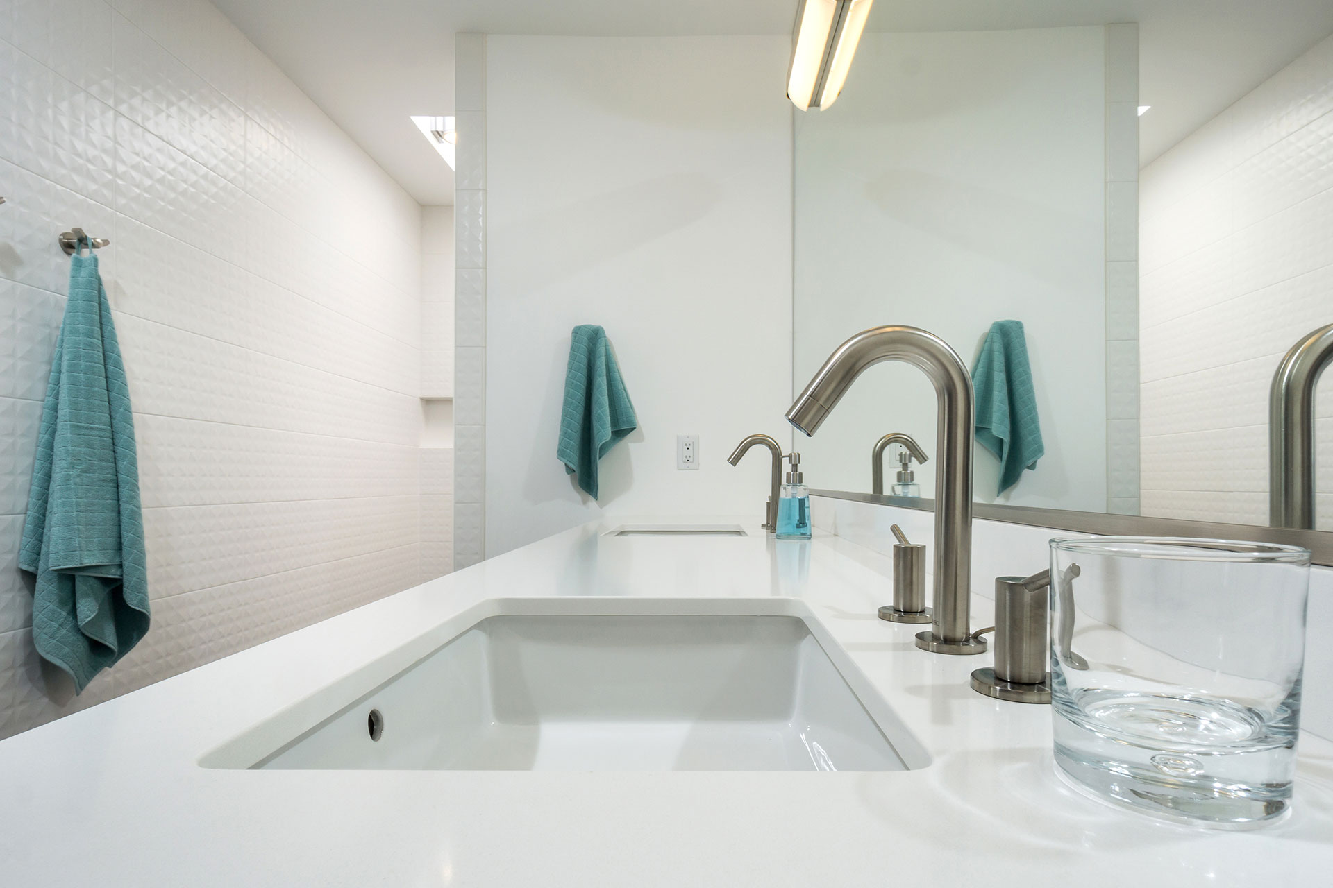 After the mid-century home remodel, the primary bathroom vanity has two sinks, a white quartz countertop, and brushed nickel faucets.