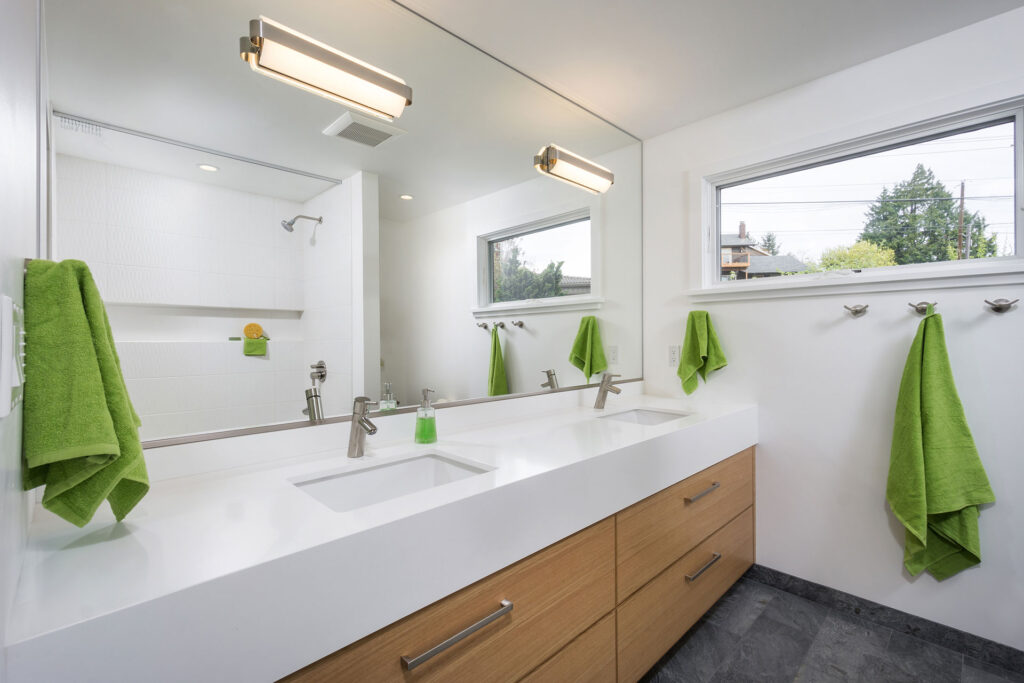 The renovated guest bathroom features a double vanity with a white quartz countertop and large mirror.