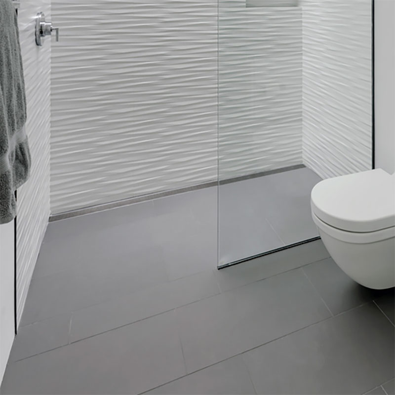 This is a walk-in shower with gray floor tile and textured white ceramic wall tile.