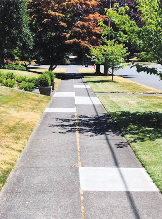 Patch repairs are visible as bright white concrete on this sidewalk.