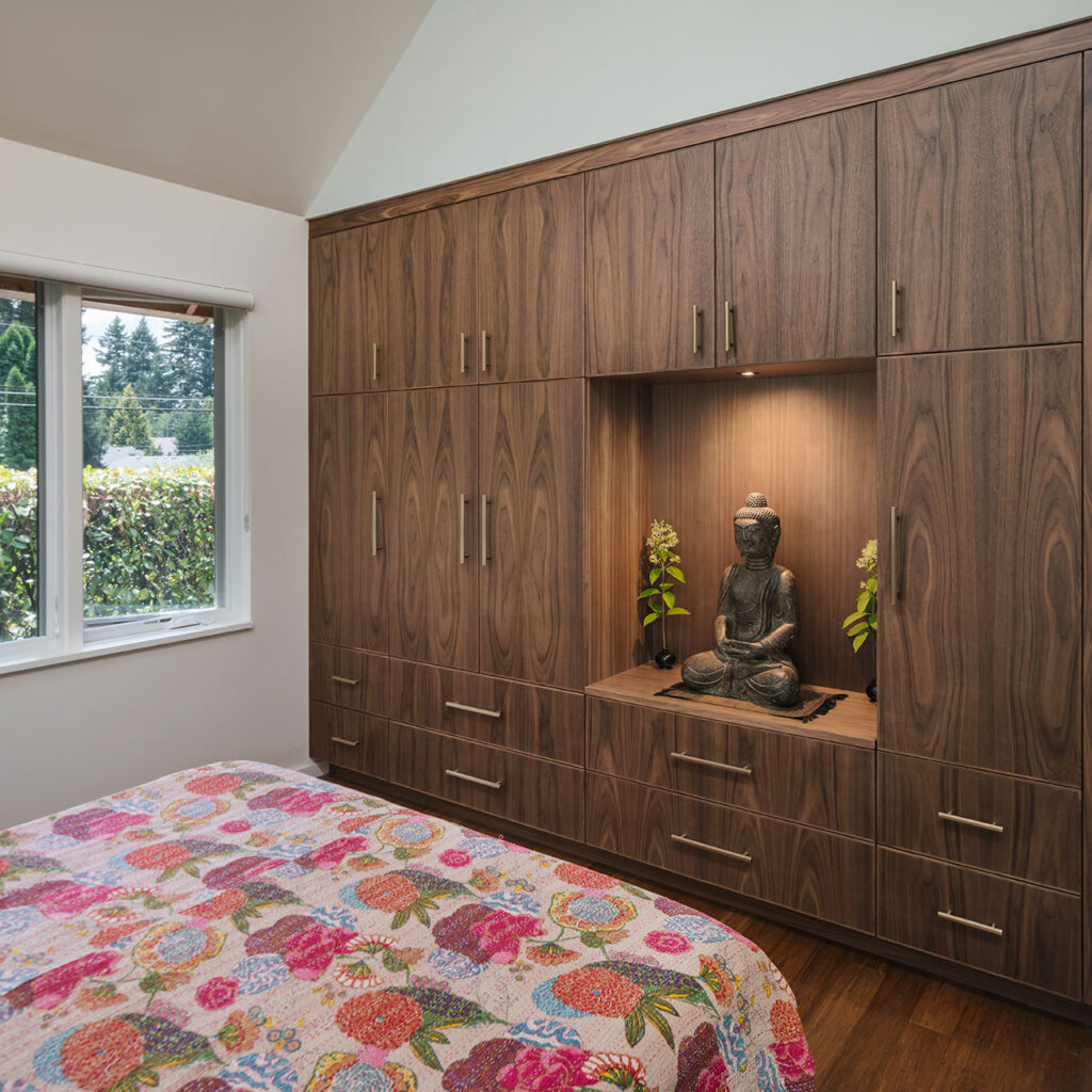 The primary bedroom has a full wall of custom plain-sliced cabinetry for clothing storage plus a niche to display a Buddha statue.