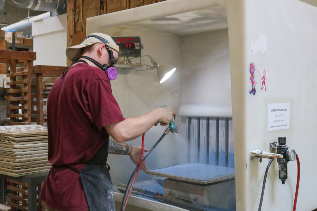 Cameron Holtcamp spraying the glaze onto tiles in the spray booth.