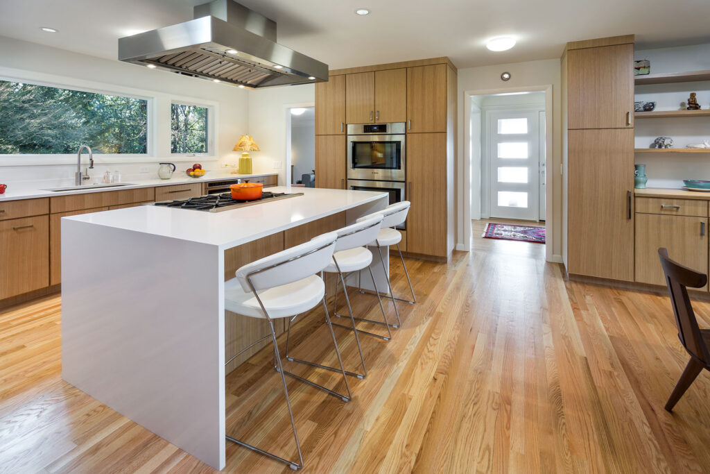 The entertainer's kitchen features a central island with a range top and island vent hood, double wall ovens, and a microwave drawer.