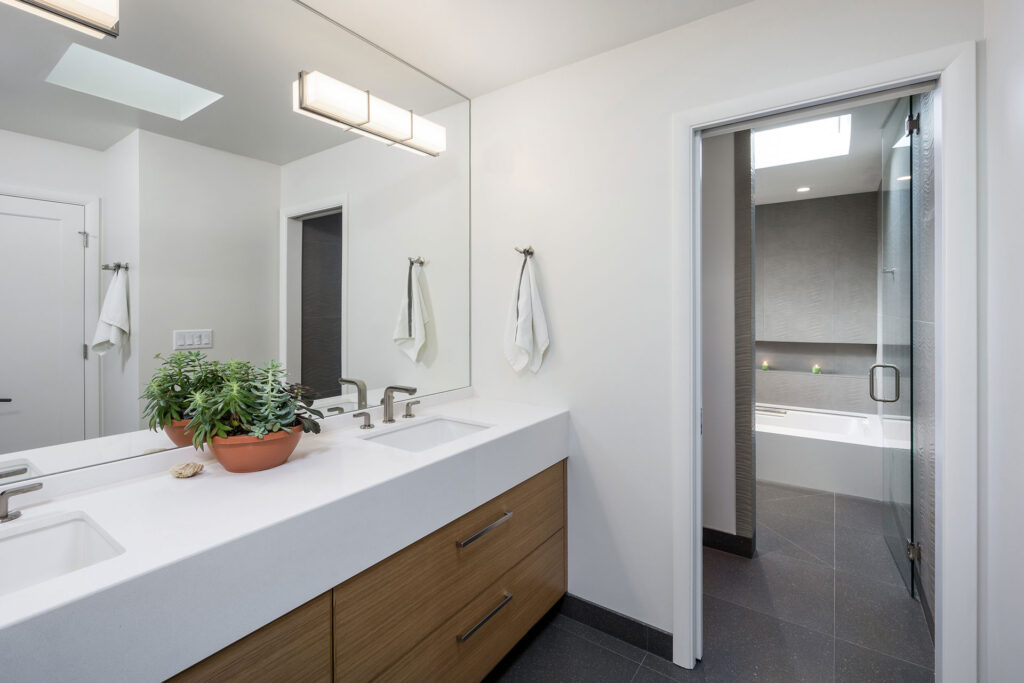 The primary bathroom vanity features two sinks and a wall to wall mirror.