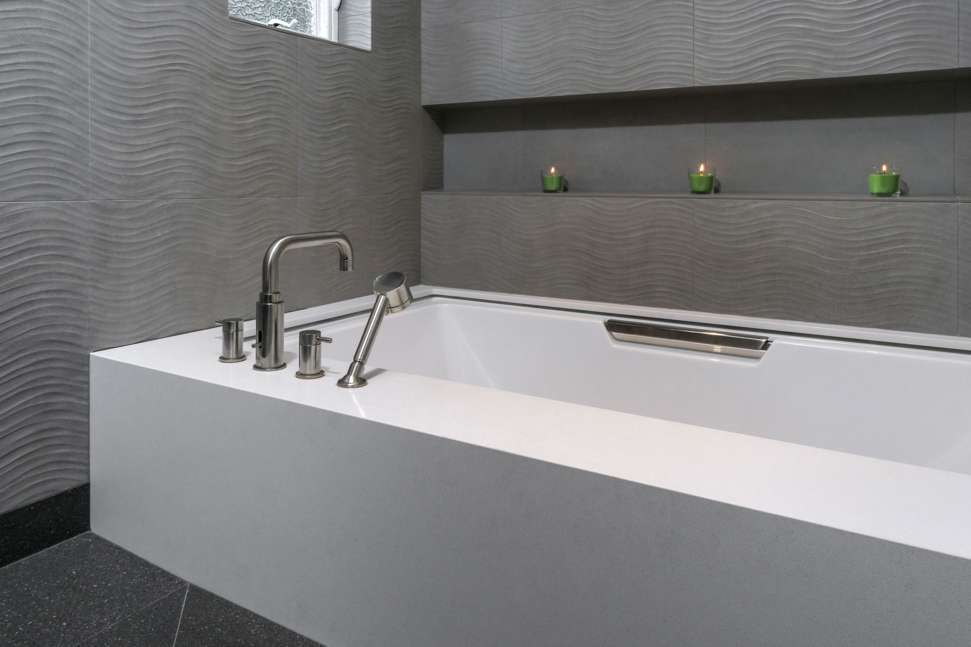 The tub in the primary bathroom is partially recessed into the floor. The surrounding wall and floor tile is porcelain.