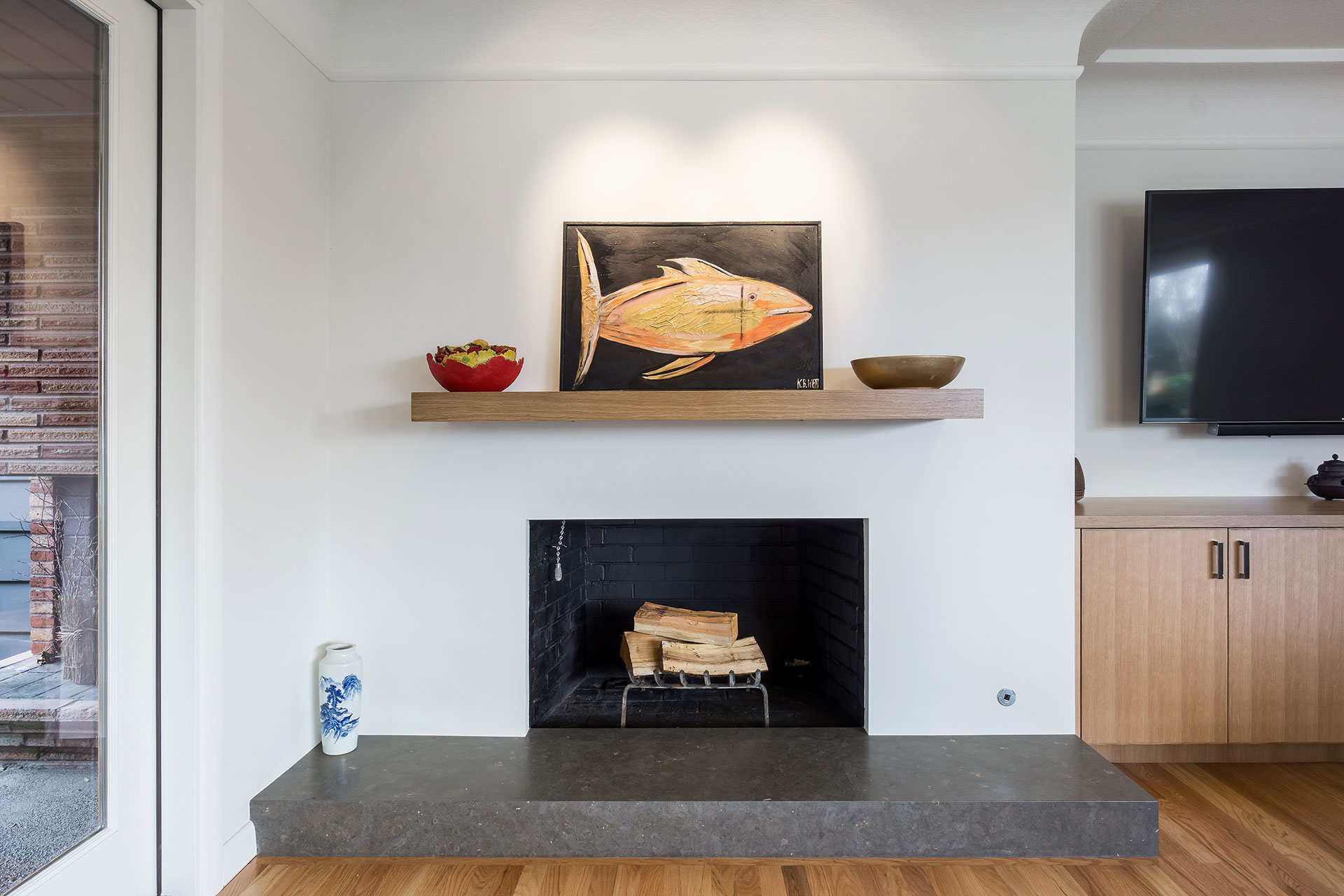 The fireplace now features a smooth wall finish, limestone hearth, and a chunky rift white oak mantle.