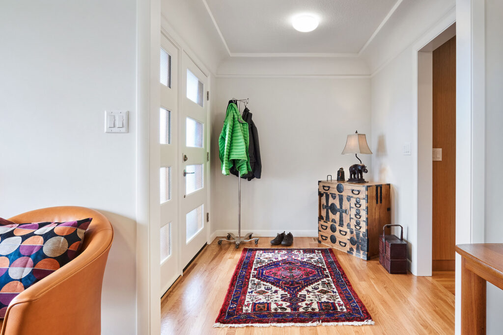 Entry hall with hardwood floors, cove moulding, and mid-century doors.